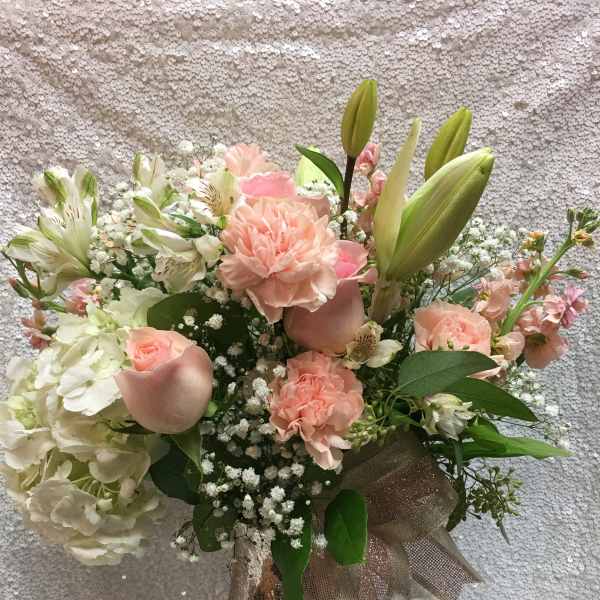 Pastel bouquet of lilies, carnations, roses, and hydrangea in a glass vase