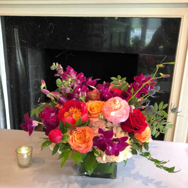 Colorful mixed flower arrangement in a square glass vase on a table