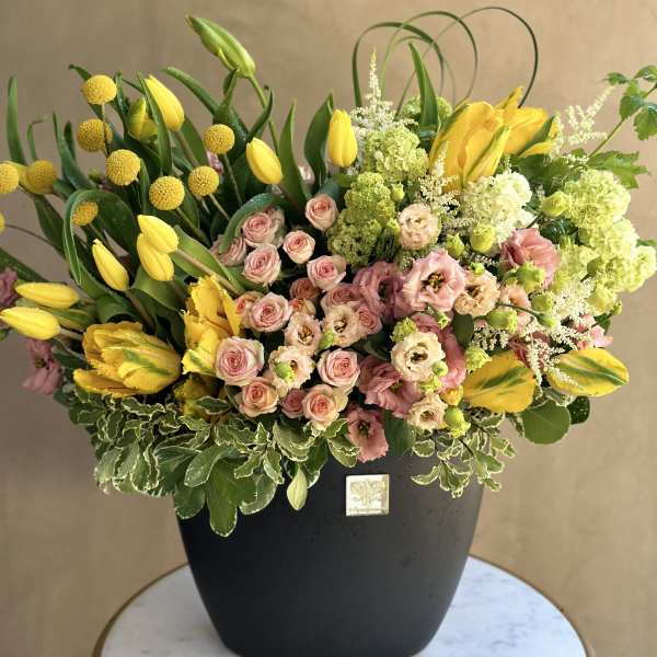 Yellow tulips and pink roses arranged in a black vase