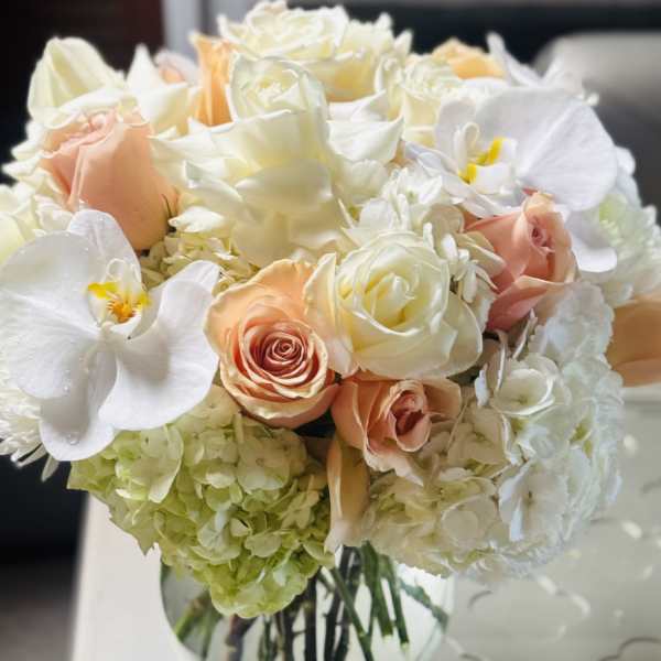 Bouquet of white and peach roses with white orchids in a glass vase