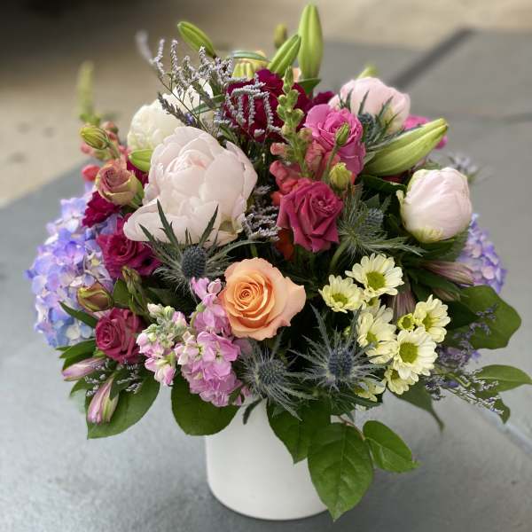 Mixed bouquet of pink, white, and peach flowers in a white vase