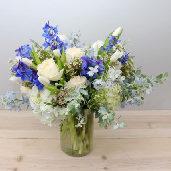 Blue and white mixed flower arrangement in a glass vase