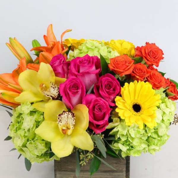 Bright mixed bouquet with roses, orchids, lilies, and a gerbera daisy in a wooden box