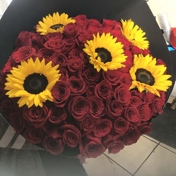 Bouquet of red roses with yellow sunflowers in black wrap