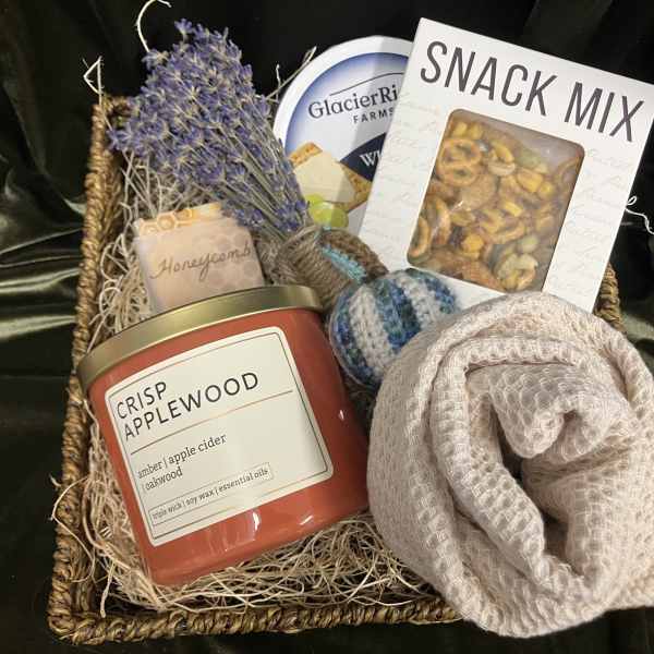 Gift basket with a candle, snack mix, soap, and a rolled knit item