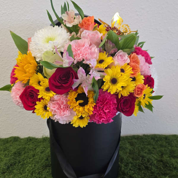 Colorful mixed bouquet in a black hatbox with roses, daisies, and carnations