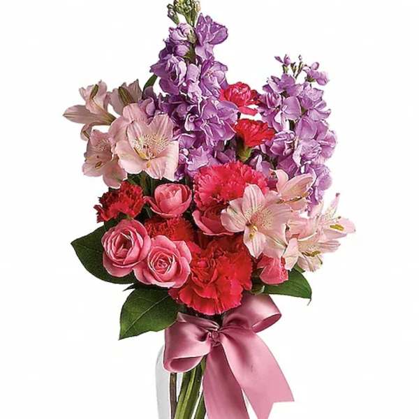 Pink and purple mixed bouquet in a clear glass vase with a satin ribbon