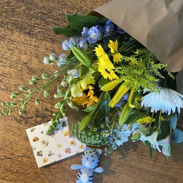 Mixed bouquet with yellow and blue flowers, plus a small crocheted teddy bear