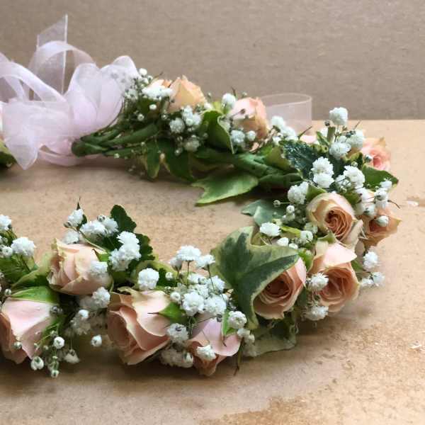 Floral wreath of pale pink roses and white baby's breath with a sheer ribbon
