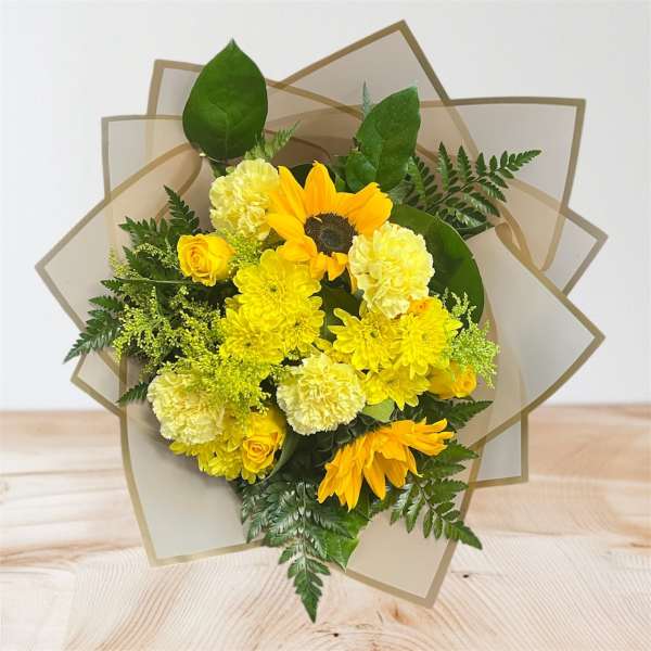 Yellow bouquet with sunflowers, roses, and carnations in tan wrap