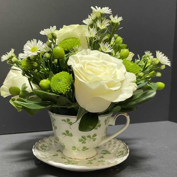 White roses and green button mums arranged in a teacup vase