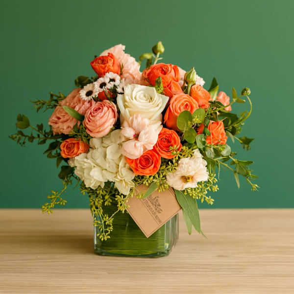 Bouquet of orange, peach, and white roses in a glass vase