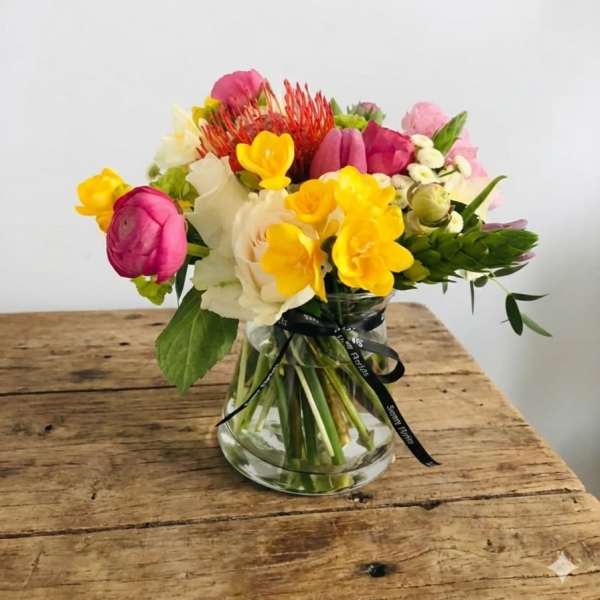 Mixed bouquet of pink, yellow, and white flowers in a glass vase