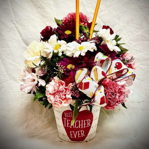 Mixed flower arrangement in a teacher-themed container with pencils and a ribbon bow