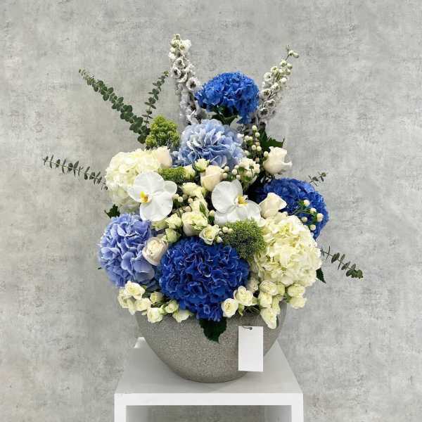 Blue and white floral arrangement in a gray vase