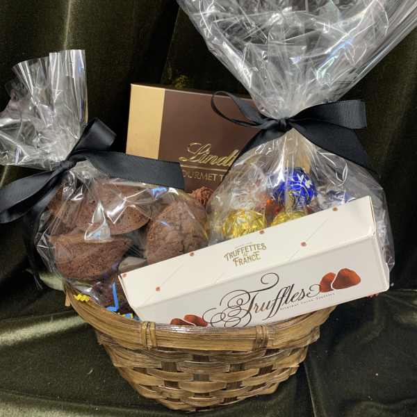 Gift basket with chocolate truffles and boxed candies wrapped in clear cellophane