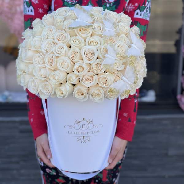Large bouquet of cream roses in a white box with gold-trimmed white bows