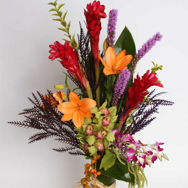 Tropical bouquet with orange lilies, red ginger, and purple orchids in a glass vase