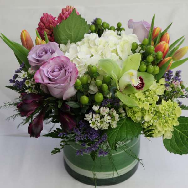 Mixed bouquet with lavender roses, white hydrangea, and green orchids in a vase