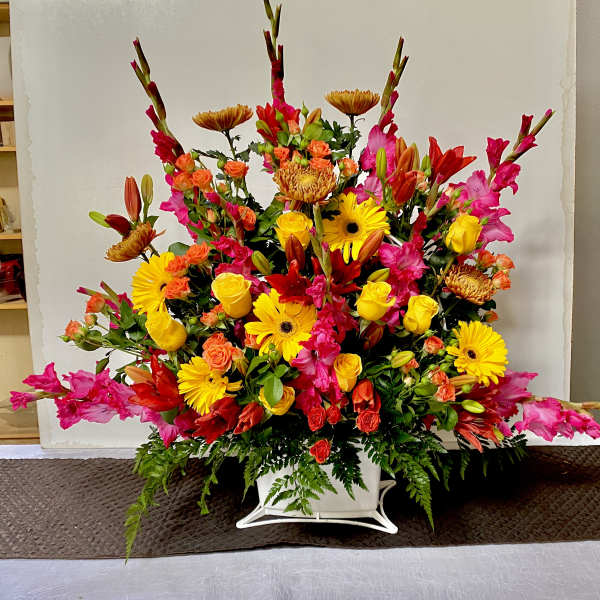 Large colorful floral arrangement in a white container