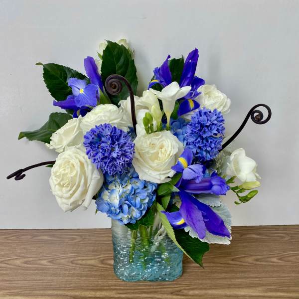 Blue and white floral arrangement in a square glass vase