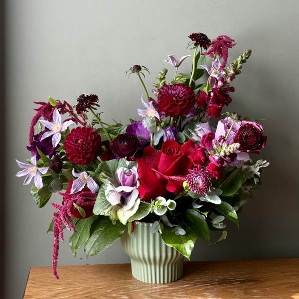 Mixed bouquet of red, pink, and lavender flowers in a ribbed vase