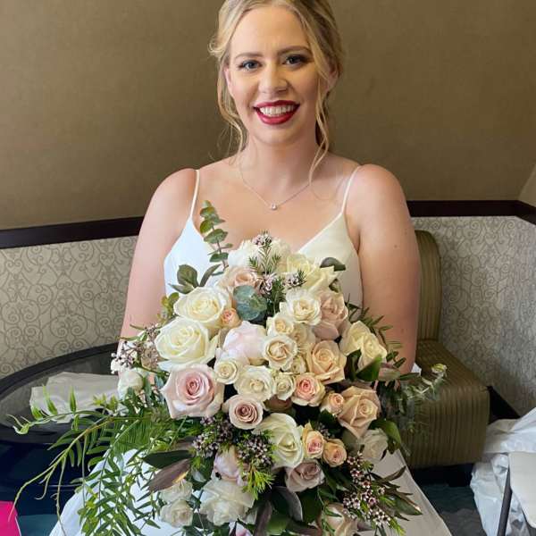 Bride holding a large bouquet of white and blush roses