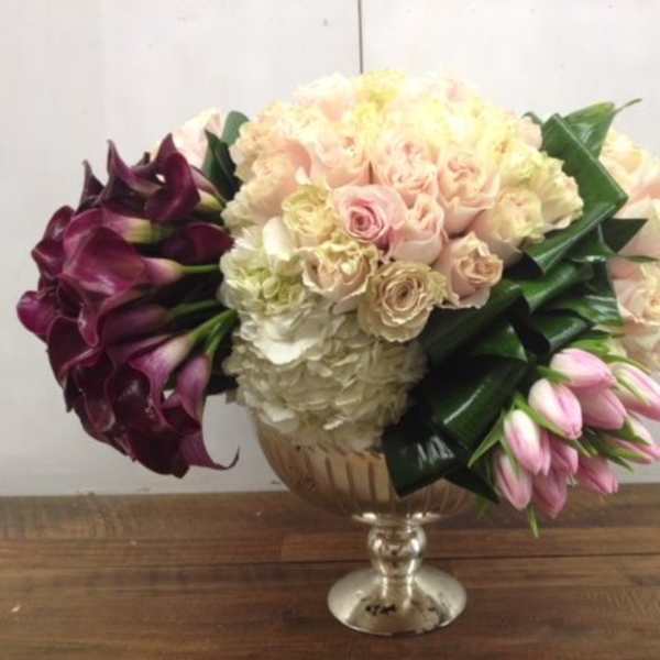 Bouquet of pale roses, hydrangeas, calla lilies, and pink tulips in a glass vase