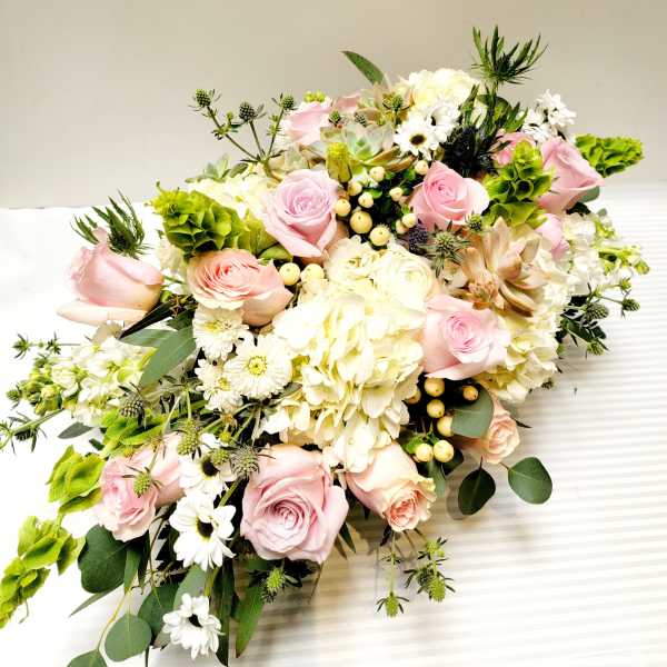 Pink roses and white hydrangeas arranged with white daisies and greenery