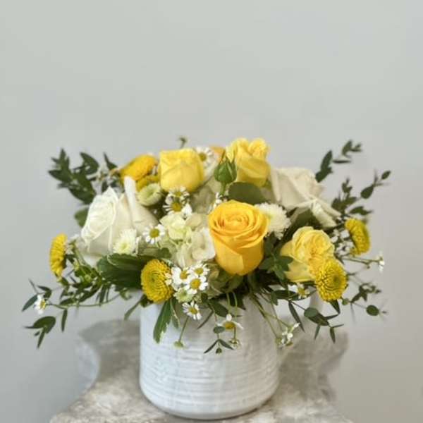 Yellow and white roses arranged in a white vase