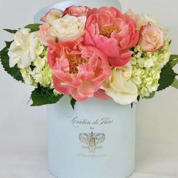 Pink and white flowers arranged in a pale blue hat box