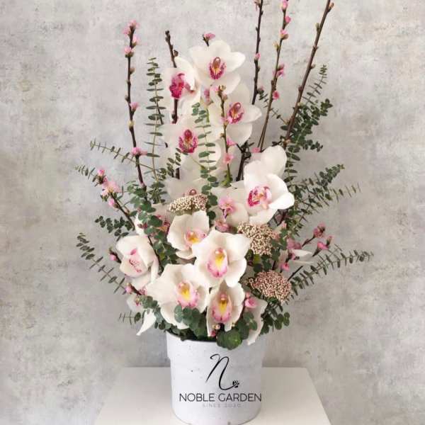 White orchids arranged in a white container with pink accents