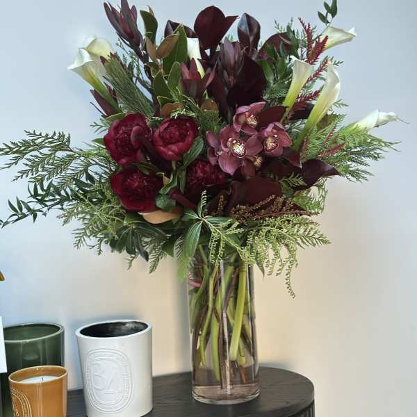 Deep burgundy bouquet with white calla lilies in a clear glass vase