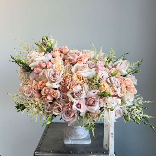 Large bouquet of blush and peach roses in a square vase