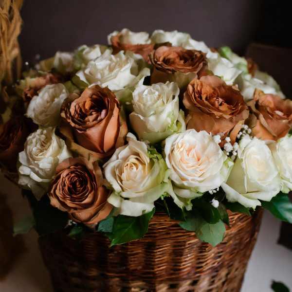 Basket of cream and copper roses with greenery