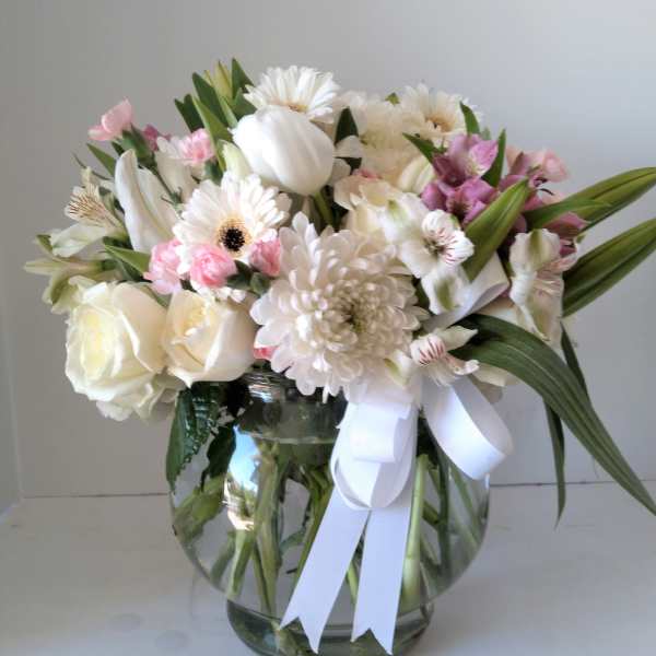 White and pink mixed bouquet in a glass vase with a white ribbon