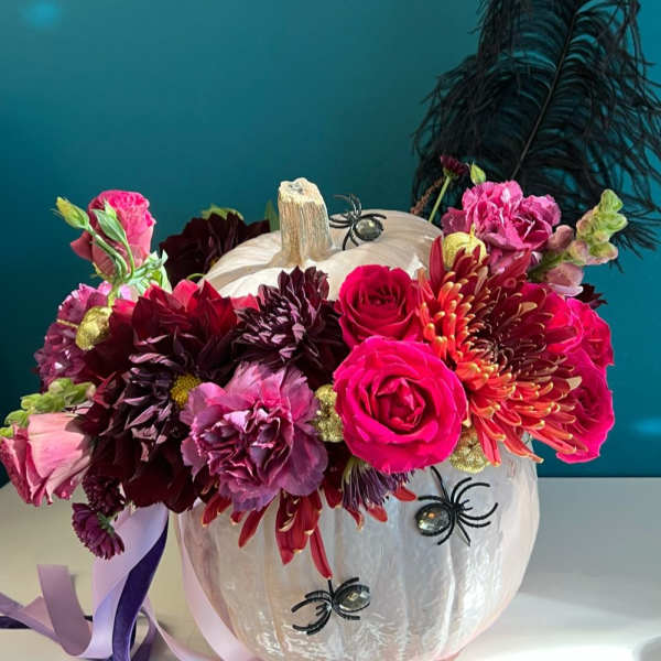 Floral arrangement in a white pumpkin with pink and burgundy blooms