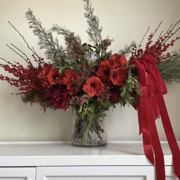 Red floral arrangement in a clear glass vase with a large red ribbon