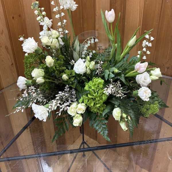 White floral arrangement with tulips and roses in a clear vase