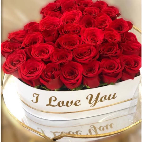 Heart-shaped box filled with red roses and I Love You text in gold script