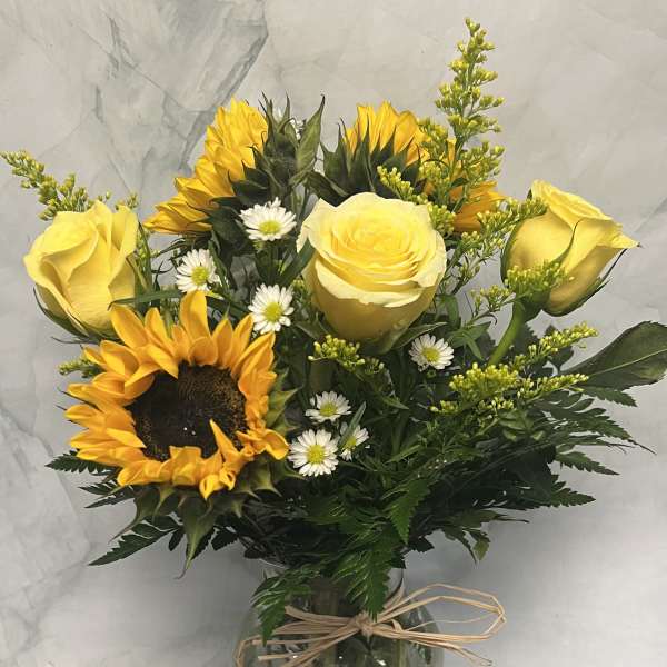 Bouquet of yellow roses and sunflowers in a glass vase