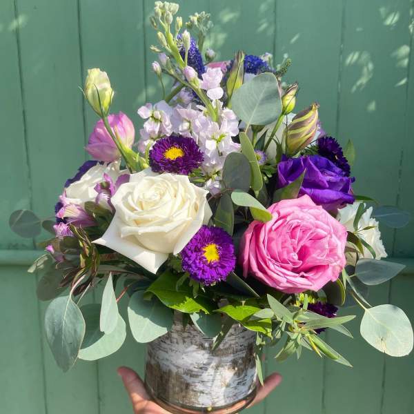 Mixed bouquet of roses and purple flowers in a glass vase