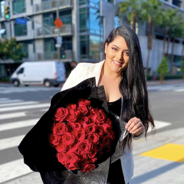 Woman holding a large bouquet of red roses wrapped in black paper