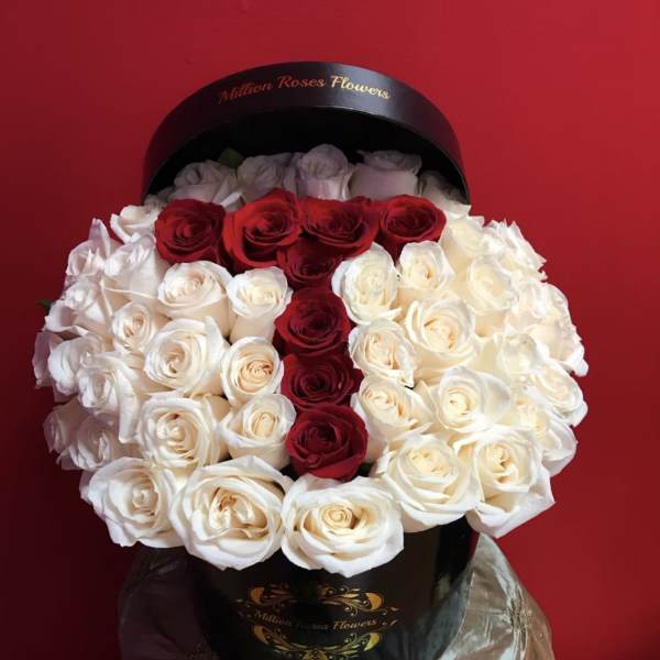 Red and white roses arranged in a black round box