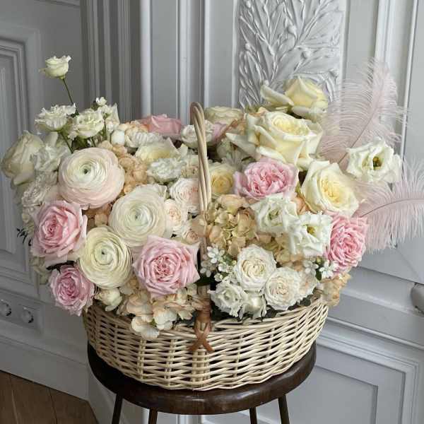 Basket arrangement of pale pink and white roses with feathers