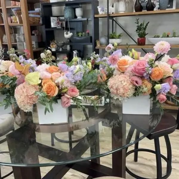 Pastel floral arrangements in white boxes on a glass table