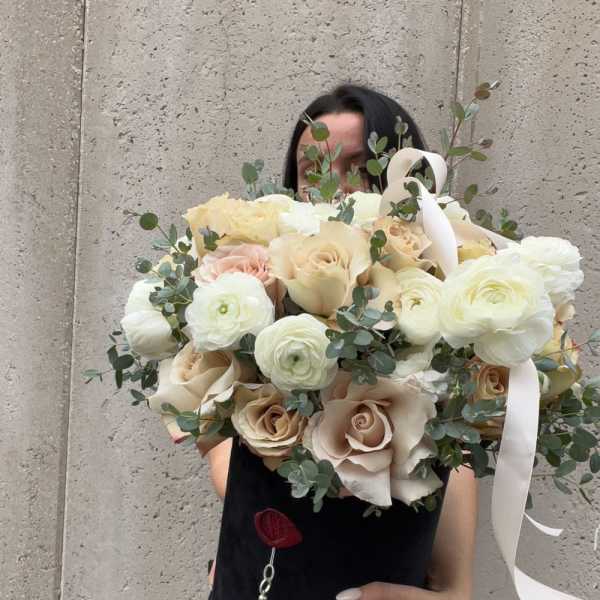 Large bouquet of cream roses and white ranunculus with eucalyptus and ribbon