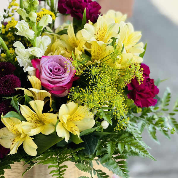 Mixed bouquet with yellow lilies, pink roses, and white snapdragons in a vase