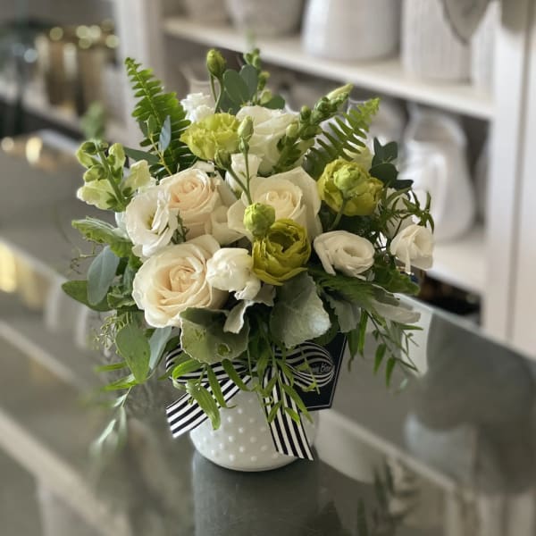 Bouquet of white and pale green flowers in a white vase with a striped ribbon