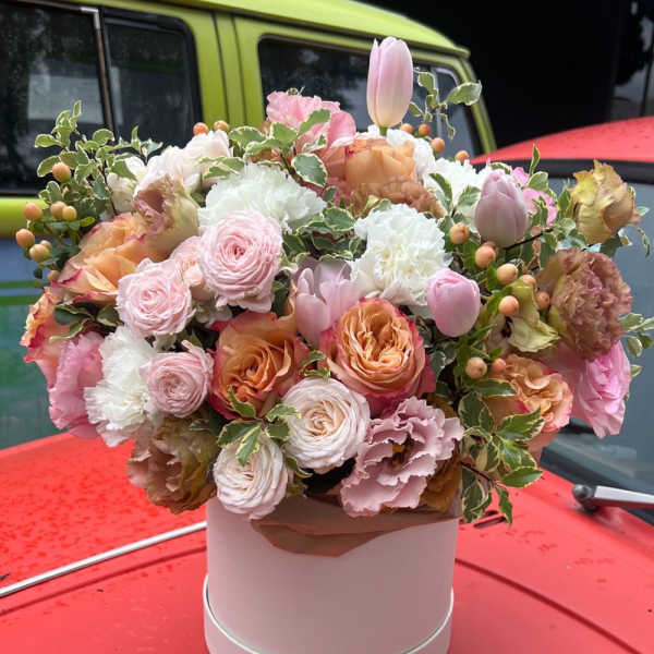 Pastel bouquet of roses, tulips, and carnations in a pink hat box